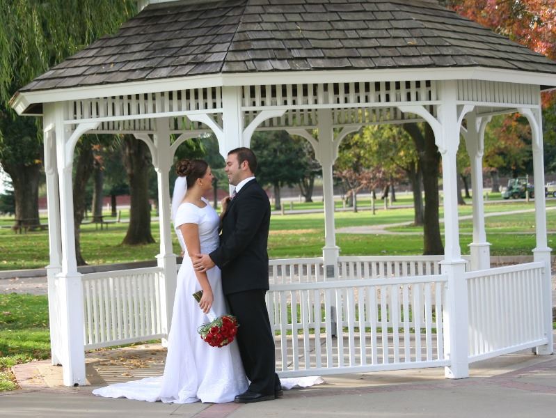 A bride and groom stand in front of a gazebo