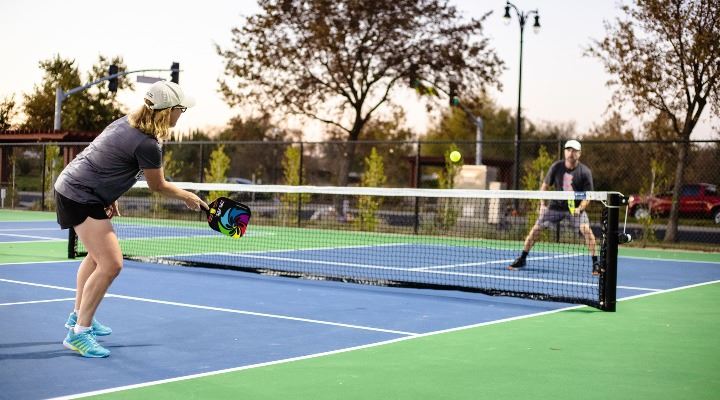 Two citizens play a game of pickleball on the courts.