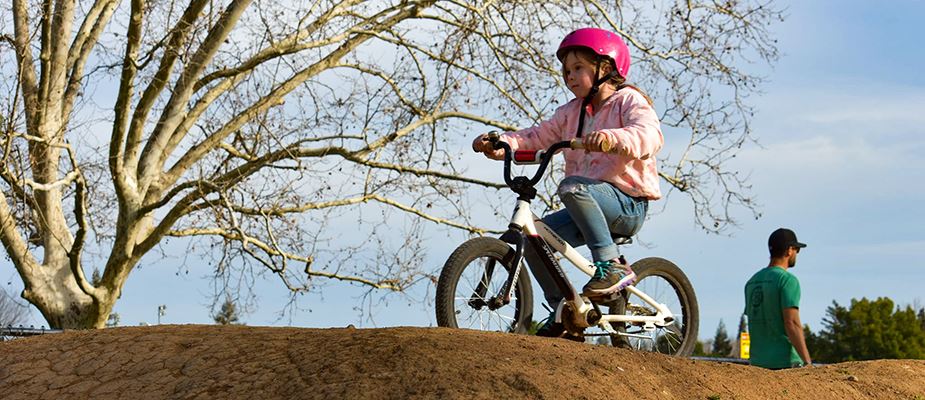 Young rider dressed in pink sits on bike, waiting and watching