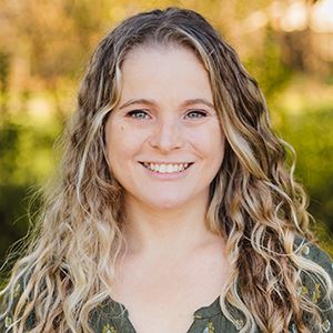 A woman with blonde, curly hair smiles.