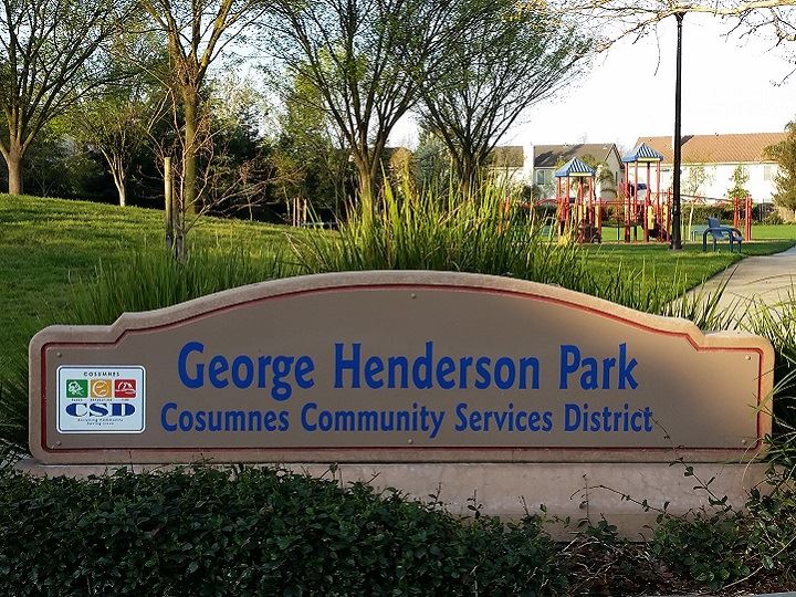 Henderson park sign with green grass and trees