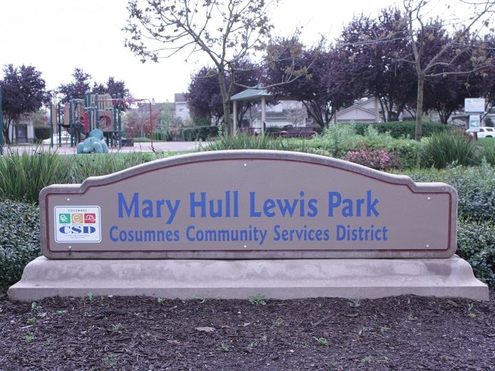 Mary Hull Lewis Park sign, with green landscape and park in the background