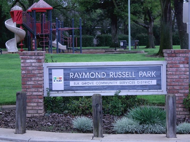 Russell Park sign with play area in background and green grass